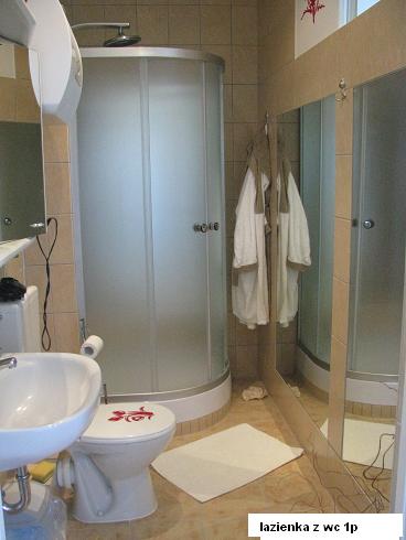 Wykończona łazienka z kabiną prysznicową, umywalką i toaletą z naklejką w Ketrzynie. Widoczne lustro i szlafrok.